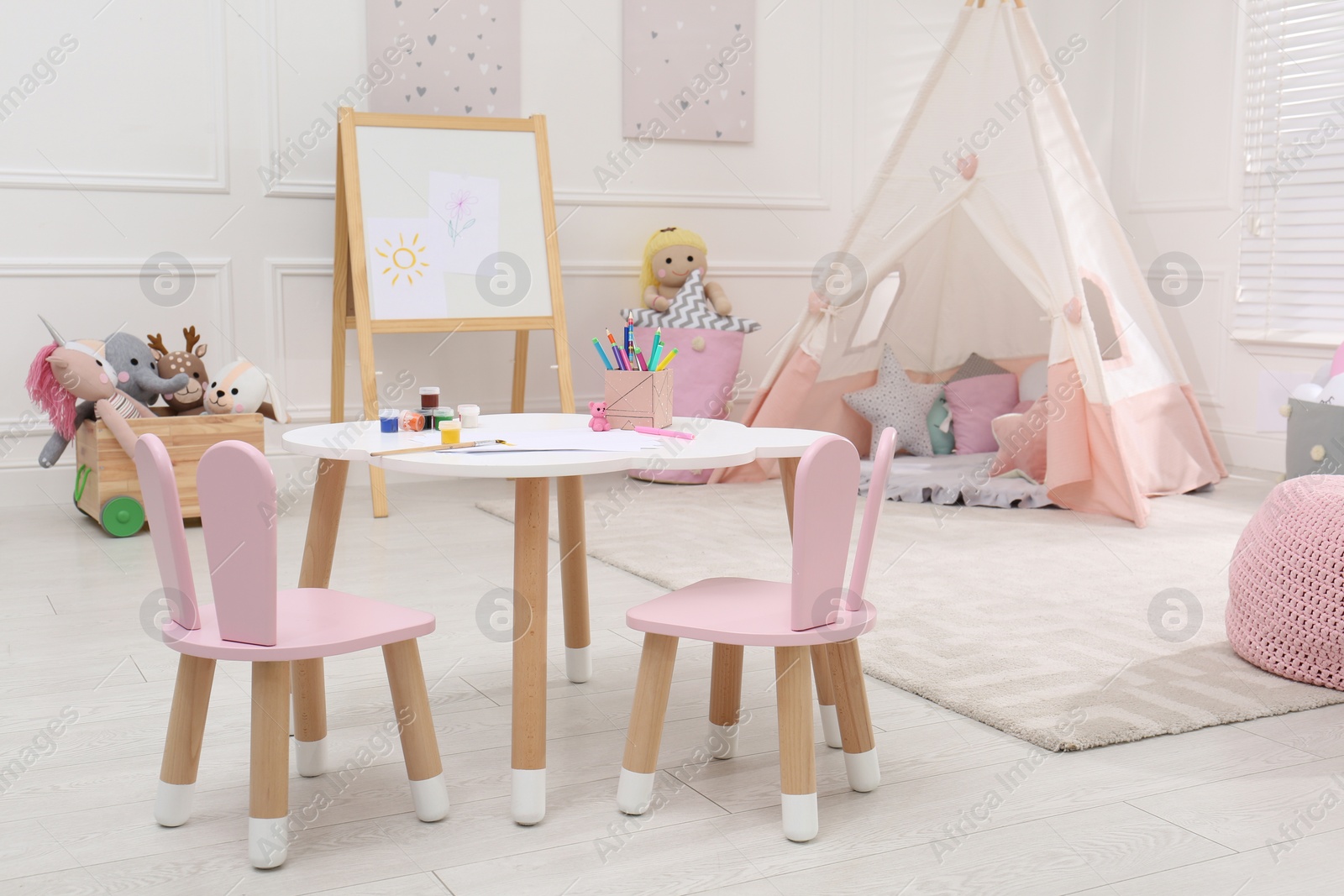 Photo of Cute child's room interior with toys, modern furniture and play tent