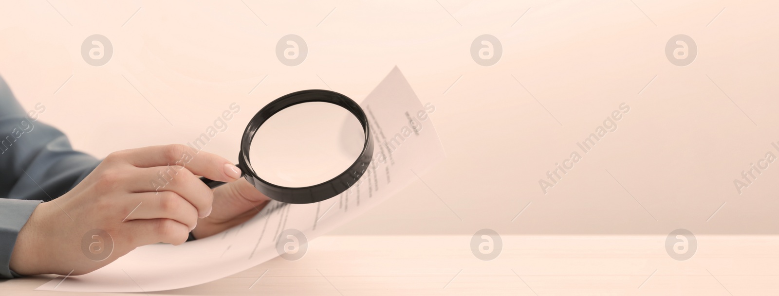 Image of Woman looking at documents through magnifier at table, closeup. Banner design with space for text