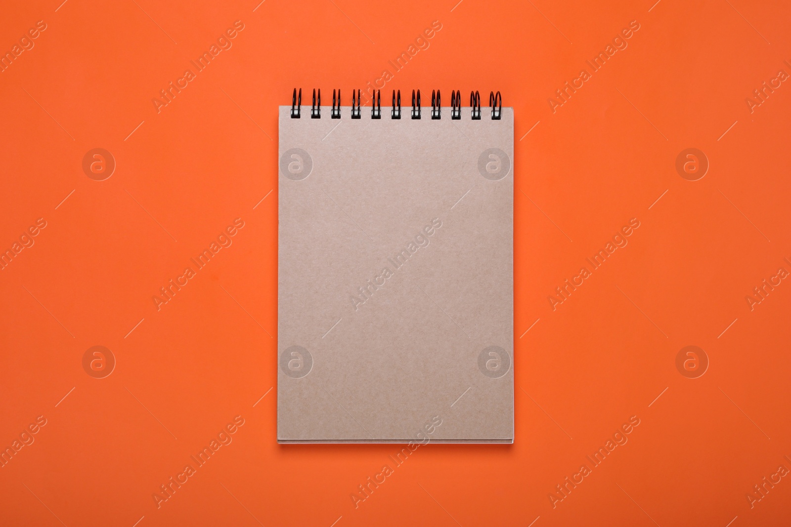 Photo of New office notebook on orange background, top view