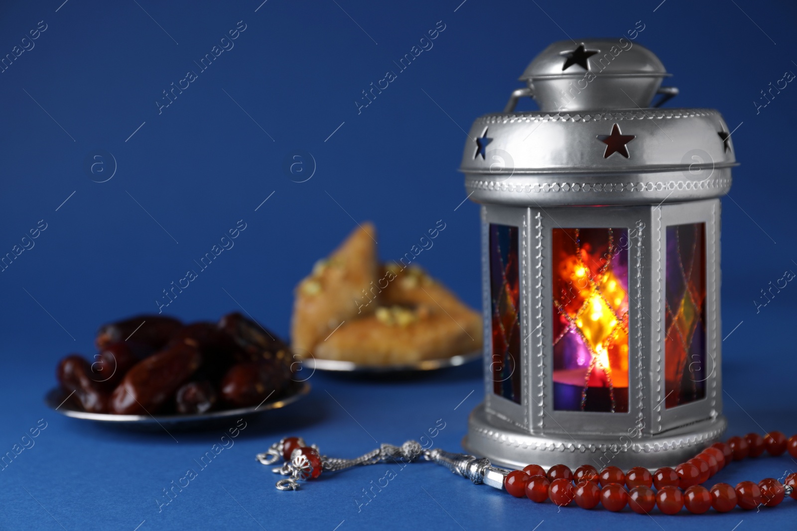 Photo of Arabic lantern and misbaha on blue background. Space for text