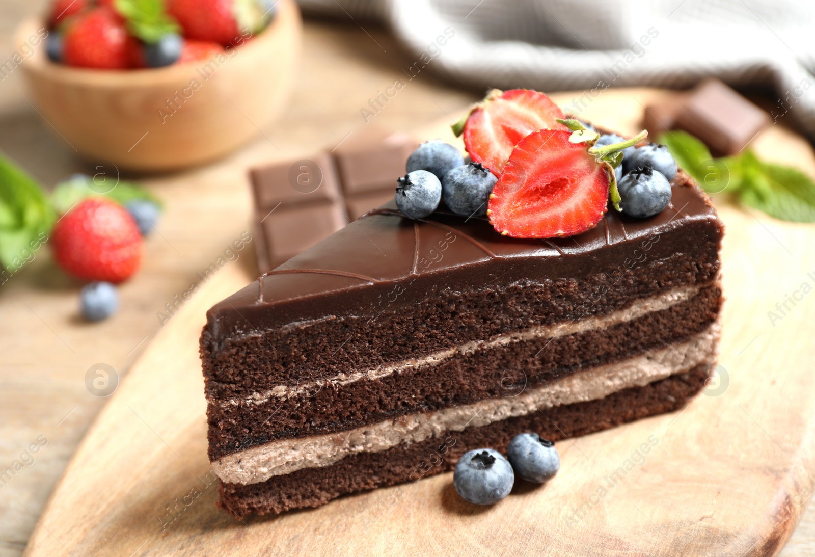 Photo of Delicious fresh chocolate cake with berries on wooden table, closeup