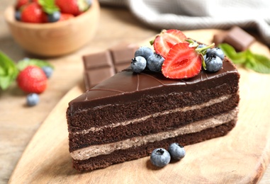 Photo of Delicious fresh chocolate cake with berries on wooden table, closeup