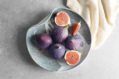 Plate with fresh ripe figs on gray background, top view