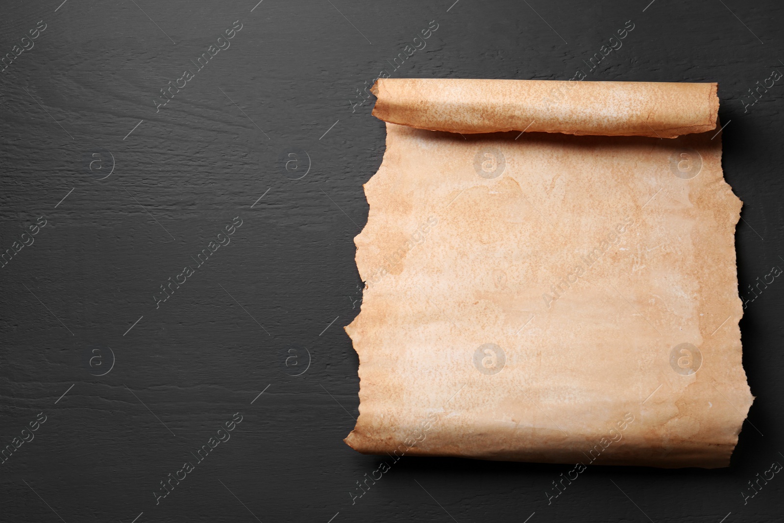 Photo of Sheet of old parchment paper on light grey wooden table, top view. Space for text