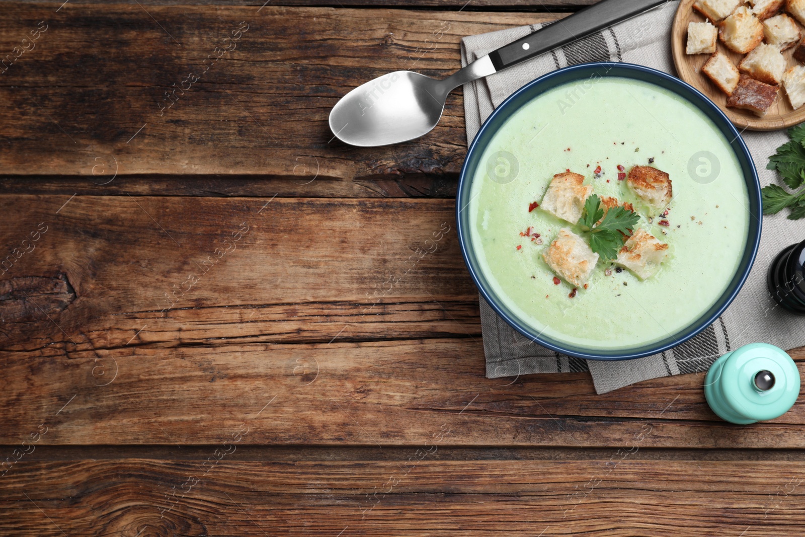Photo of Delicious asparagus soup with croutons served on wooden table, flat lay. Space for text