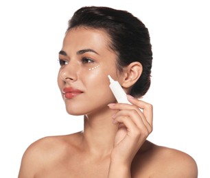 Woman applying cream under eyes on white background. Skin care