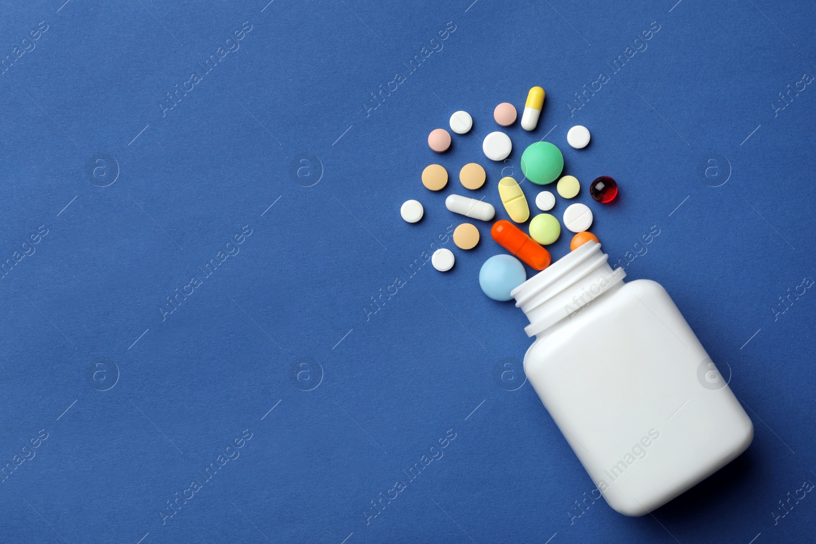 Photo of Bottle with different pills on color background, flat lay. Space for text