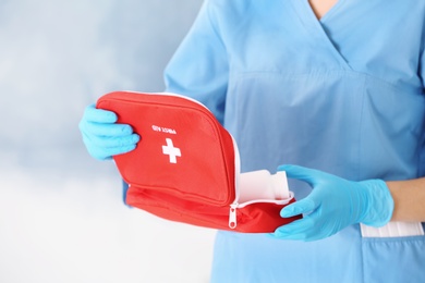 Photo of Doctor in medical gloves with first aid kit on color background