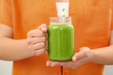 Woman holding mason jar with delicious smoothie, closeup view