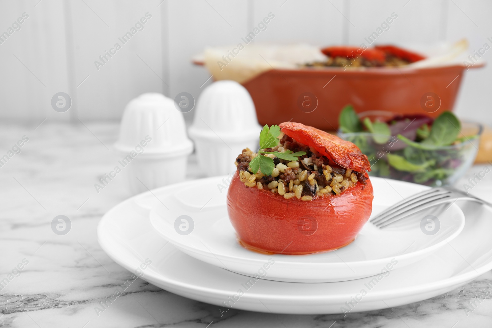 Photo of Delicious stuffed tomato with minced beef, bulgur and mushrooms on white marble table. Space for text