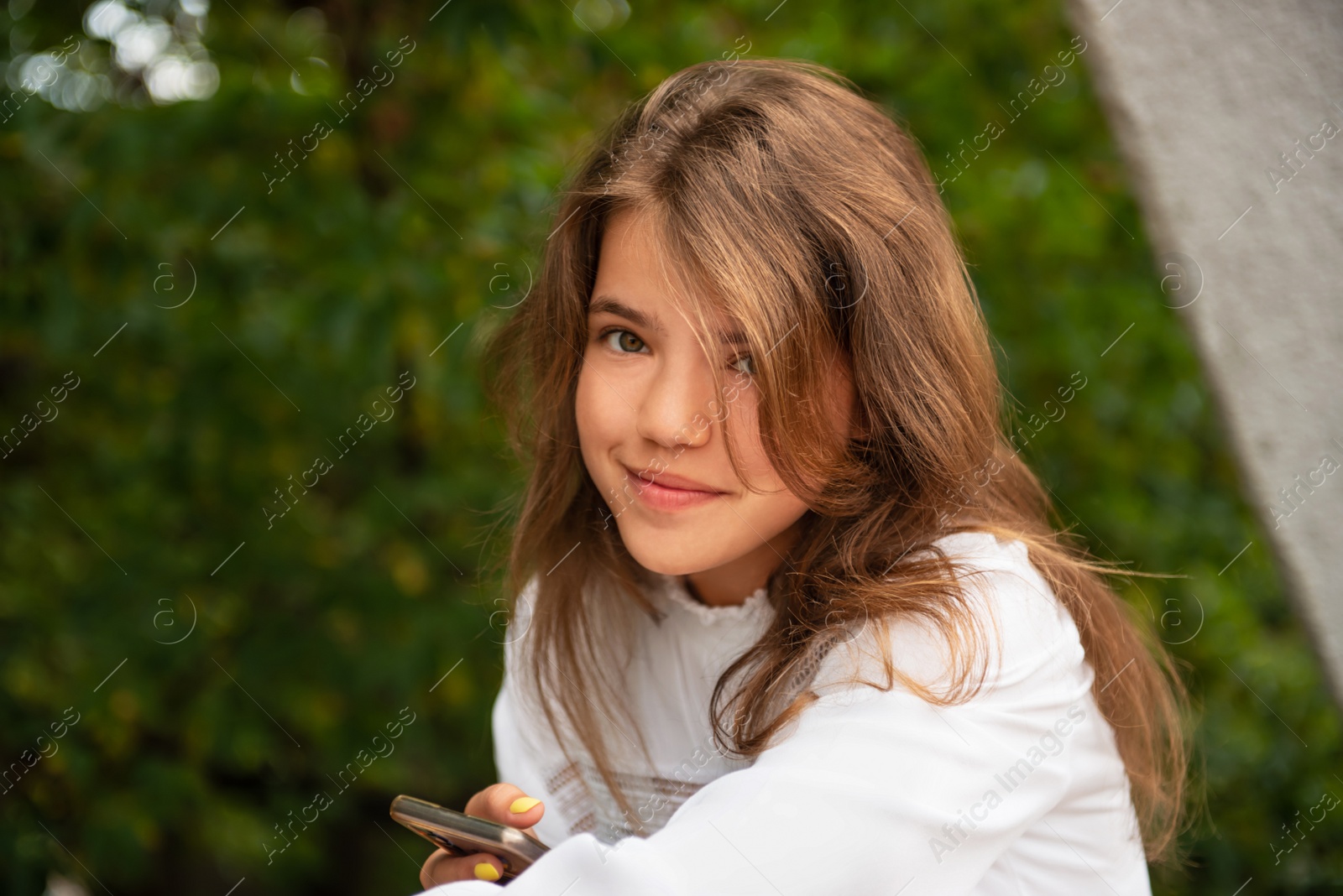Photo of Teenage girl using smartphone outdoors, space for text