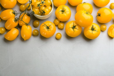 Photo of Ripe yellow tomatoes on grey table, flat lay. Space for text