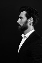 Profile portrait of handsome bearded man on black background. Black and white effect