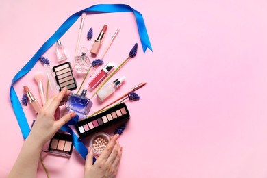 Photo of Woman with different makeup products and beautiful spring flowers on pink background, top view. Space for text