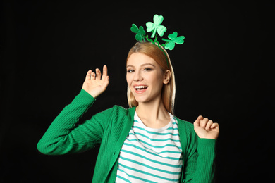 Photo of Young woman with clover headband on black background. St. Patrick's Day celebration