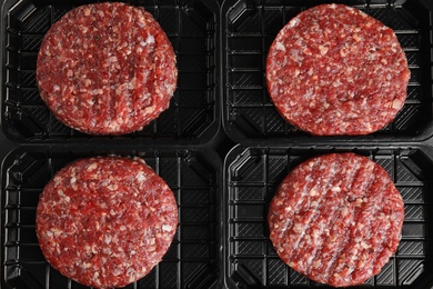 Photo of Plastic containers with raw meat cutlets for burger, top view