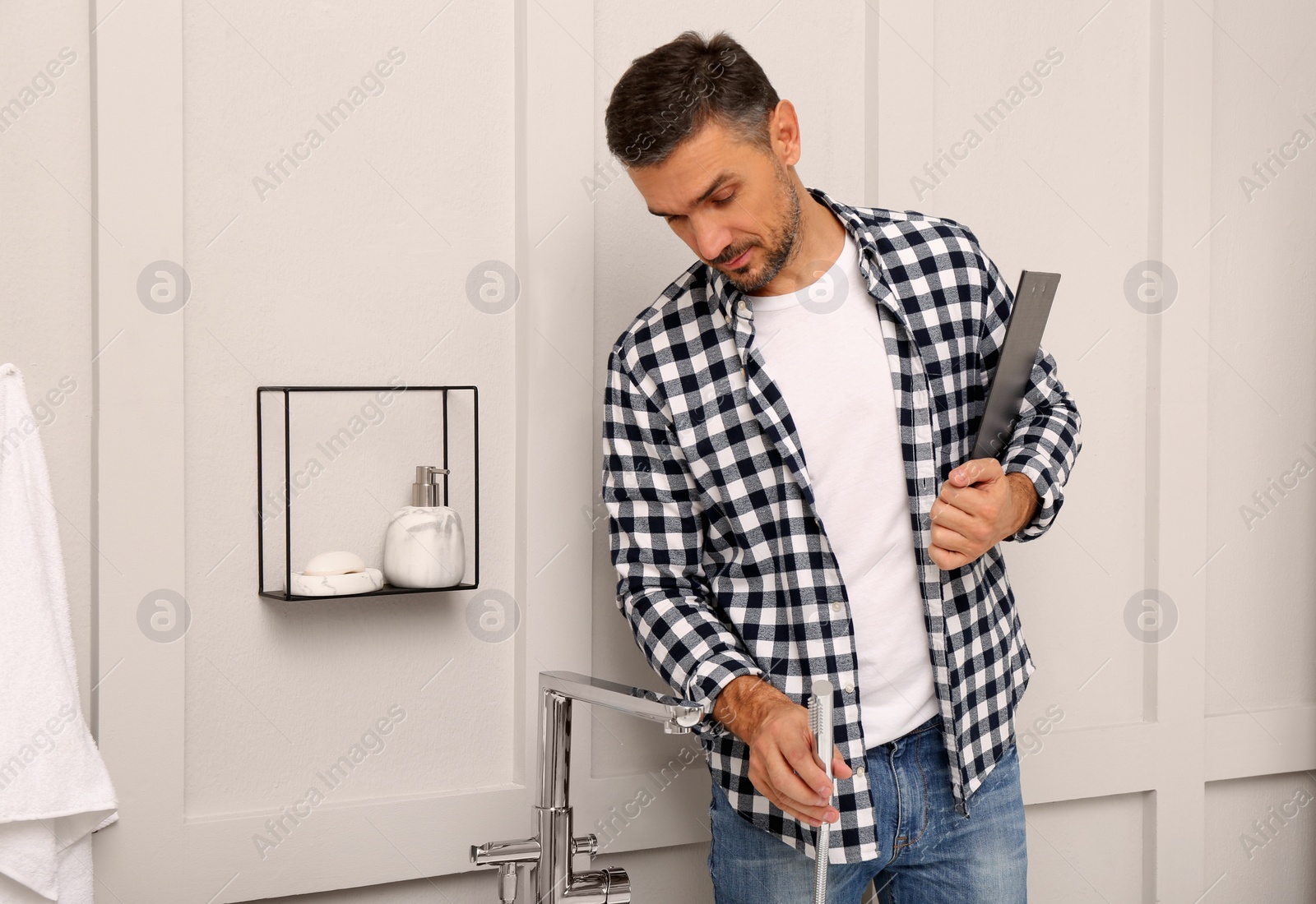 Photo of Plumber with clipboard checking water tap in bathroom