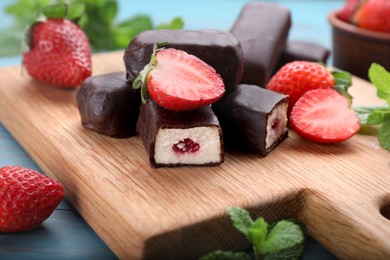 Photo of Delicious glazed curd snacks with fresh strawberries and mint on wooden board, closeup