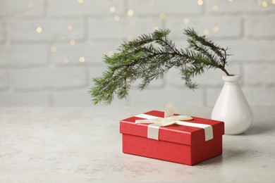 Beautiful gift box and vase with spruce tree on light grey table. Space for text
