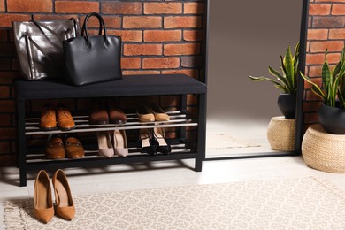 Photo of Stylish hallway with shoe storage bench and mirror near brick wall. Interior design