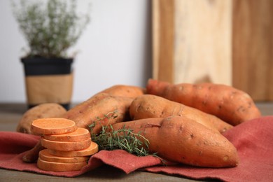 Napkin with thyme and sweet potatoes on table, closeup