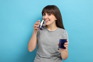 Photo of Young woman using mouthwash on light blue background