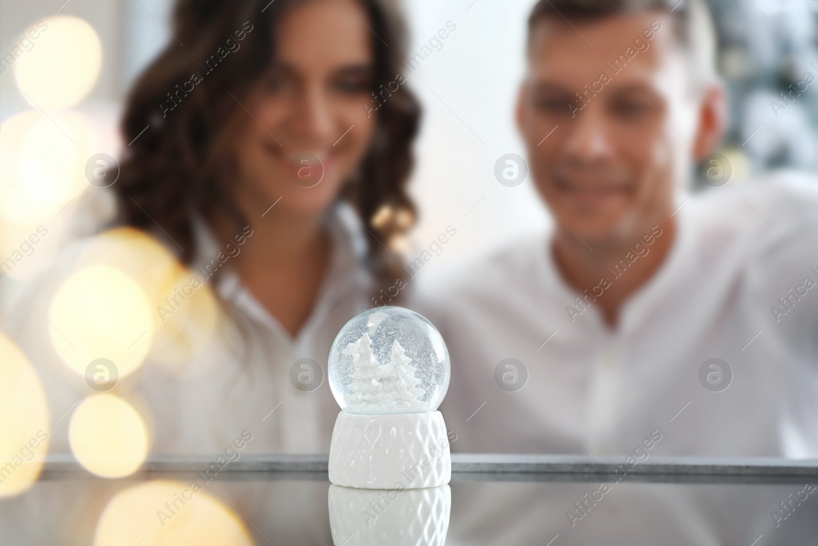 Photo of Snow globe on mirror surface. Happy couple celebrating Christmas