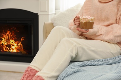 Photo of Woman with cup of cocoa near fireplace, closeup