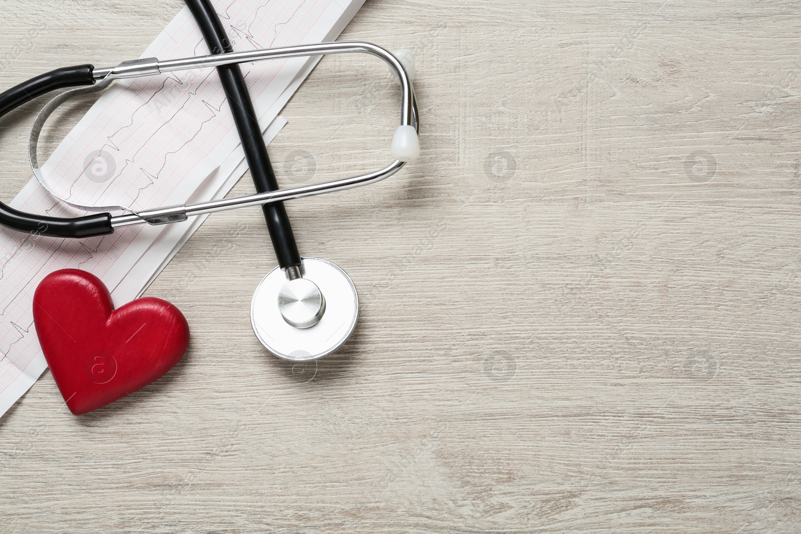 Photo of Cardiogram report, red heart and stethoscope on wooden table, flat lay. Space for text