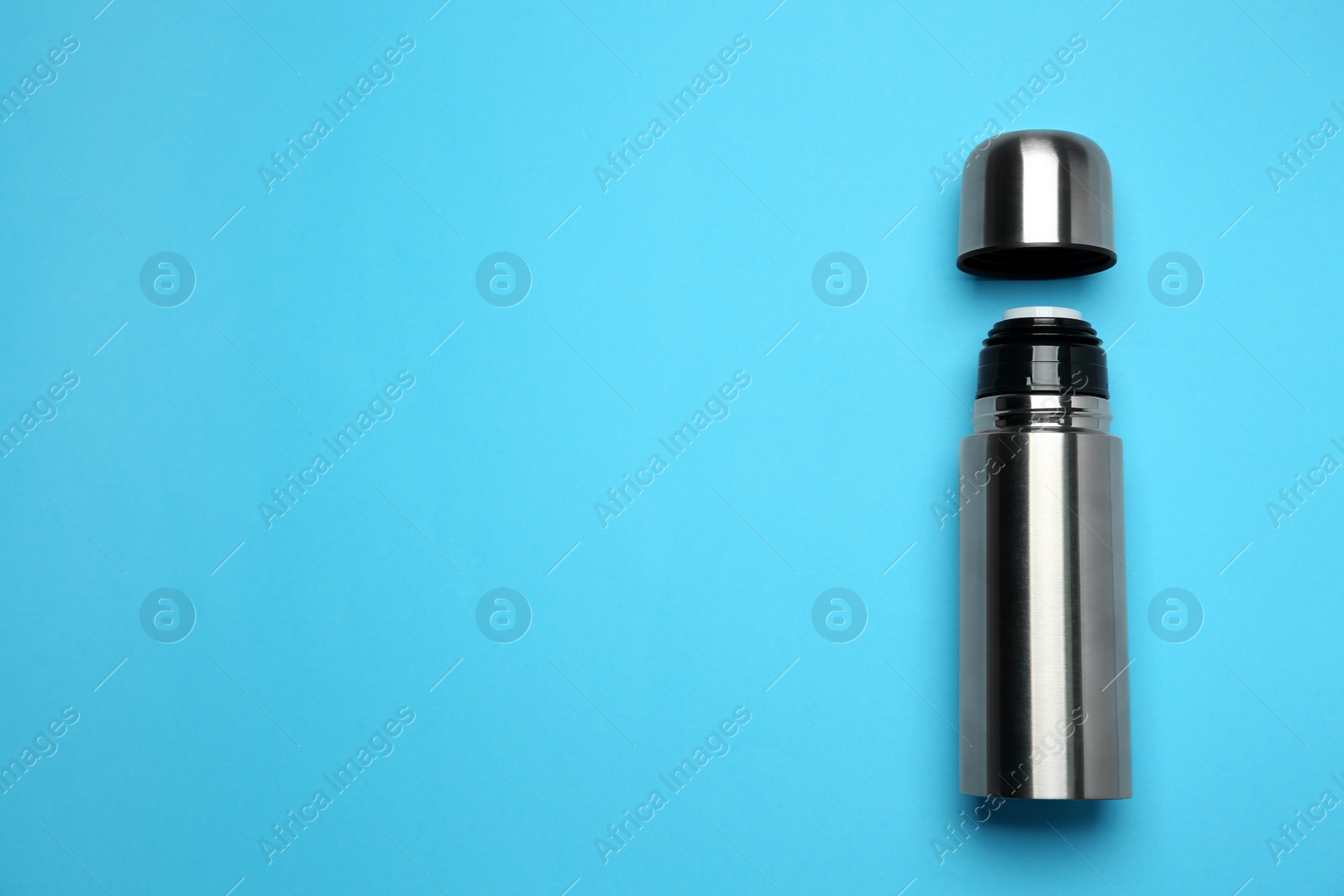 Photo of Stainless steel thermos on light blue background, top view. Space for text