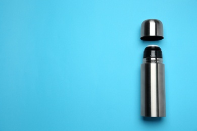 Stainless steel thermos on light blue background, top view. Space for text