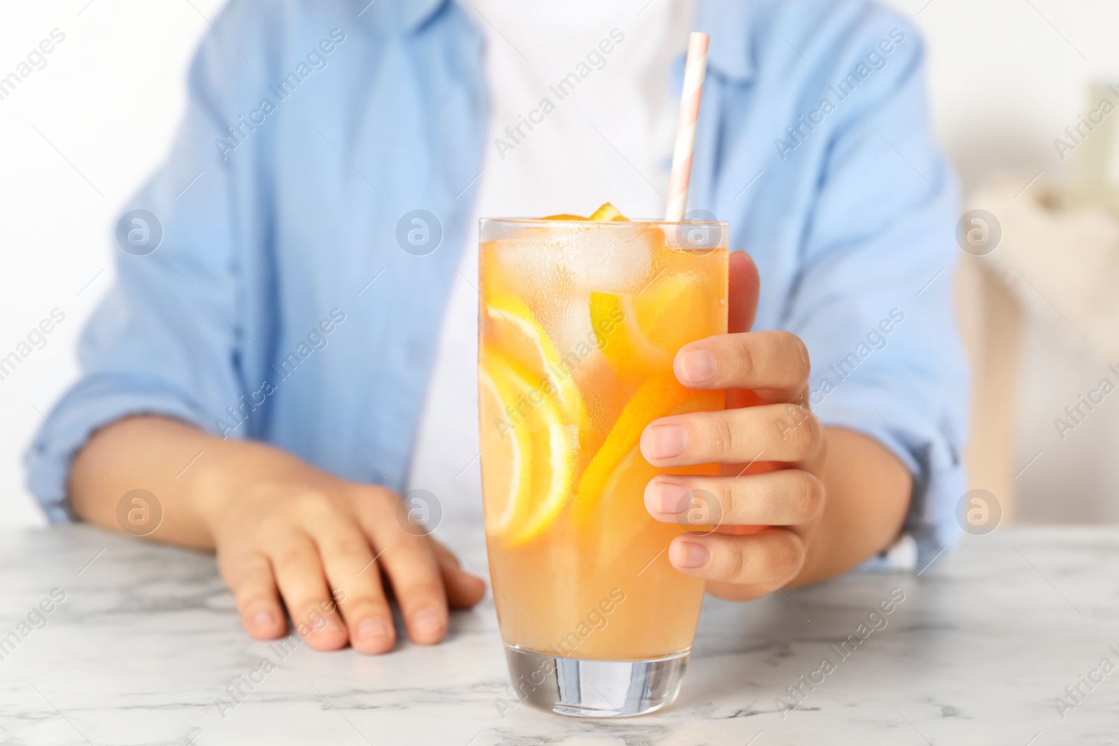 Photo of Woman with glass of orange refreshing drink at marble table, closeup