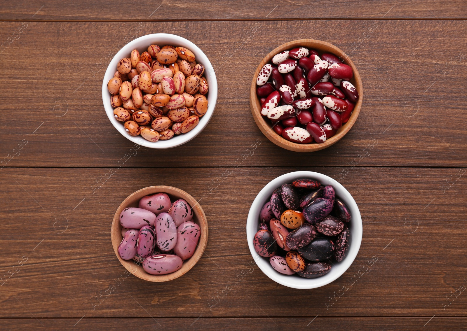 Photo of Different kinds of dry kidney beans on wooden table, flat lay