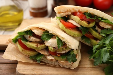 Photo of Delicious pita sandwich with grilled vegetables and parsley on wooden table, closeup