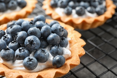 Photo of Delicious sweet pastry with berries on cooling rack, closeup