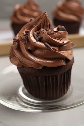 Photo of Delicious chocolate cupcake with cream and crumbles on light grey table, closeup