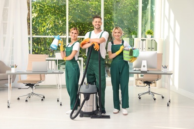 Photo of Team of janitors with cleaning supplies in office