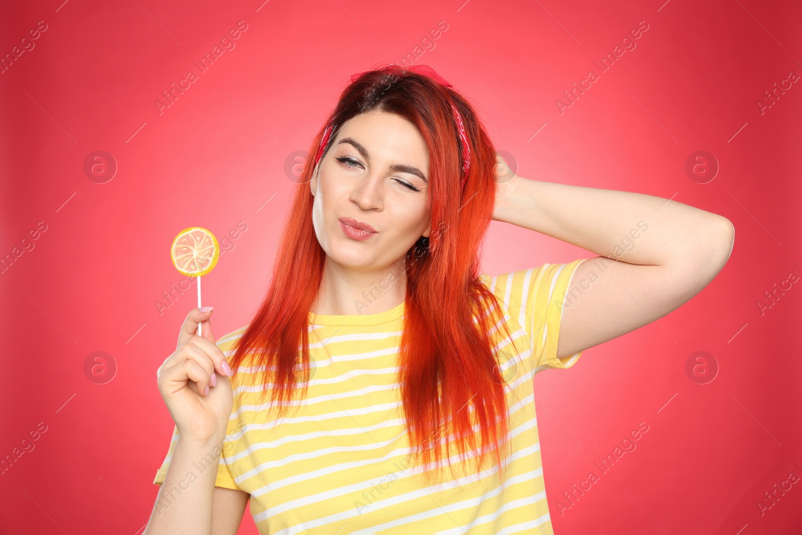 Photo of Young woman with bright dyed hair holding lollipop on red background