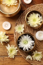 Tibetan singing bowls, beautiful chrysanthemum flowers and burning candles on wooden table, flat lay