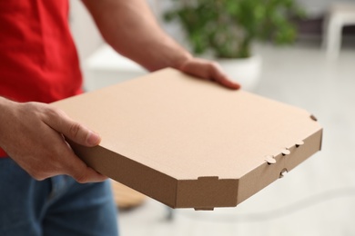 Photo of Courier with pizza box on blurred background, closeup. Space for text