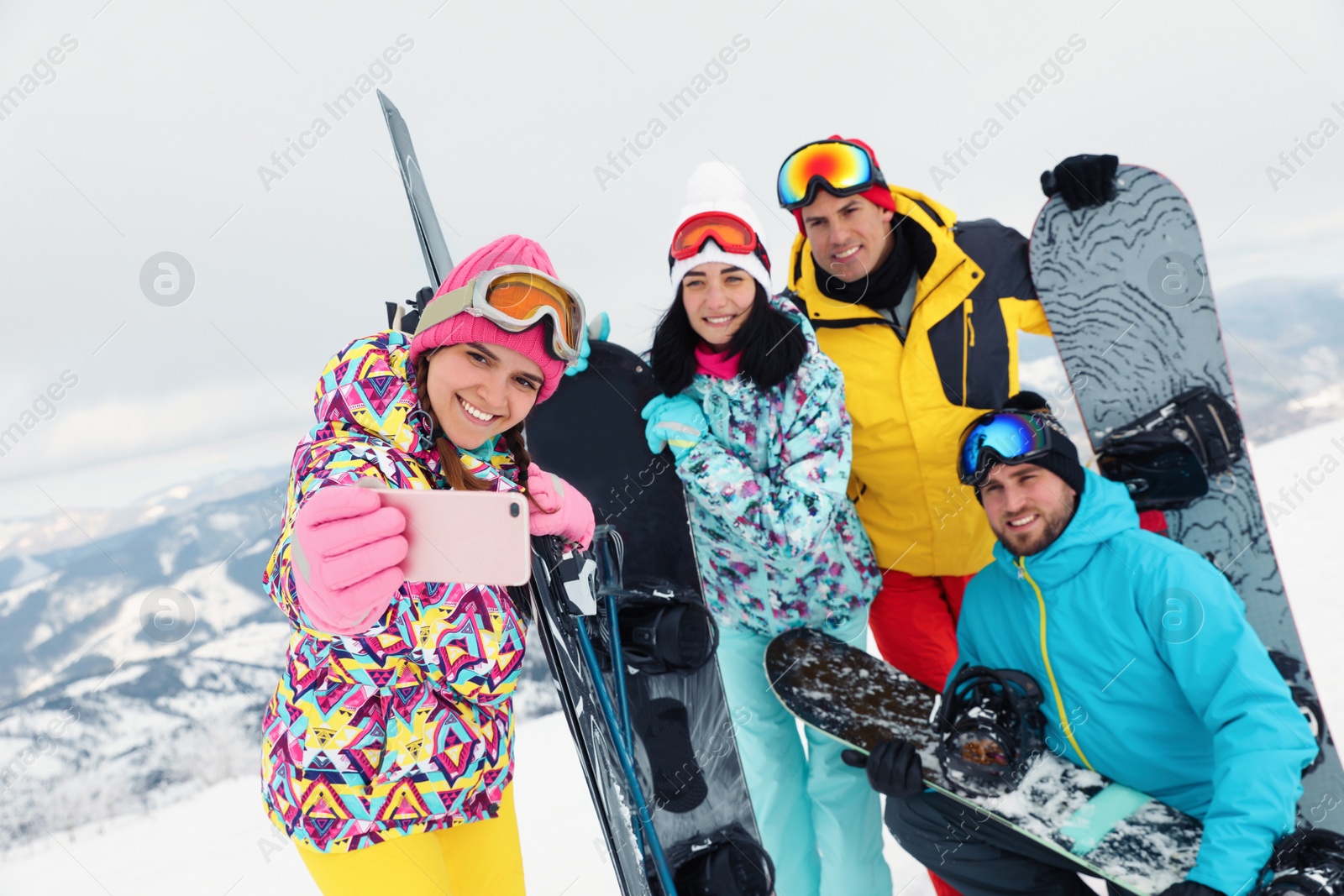 Photo of Group of friends taking selfie in snowy mountains. Winter vacation