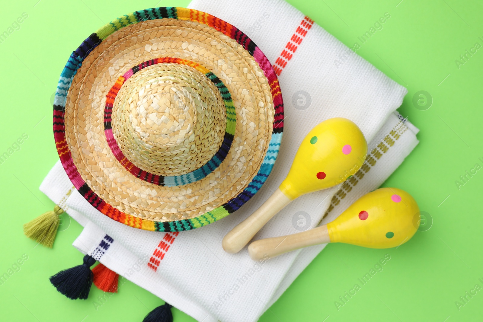 Photo of Mexican sombrero hat, maracas and poncho on green background, flat lay
