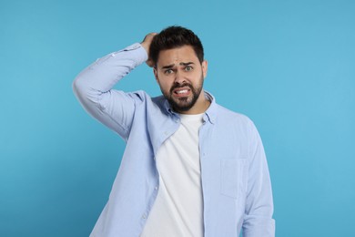 Portrait of embarrassed man on light blue background