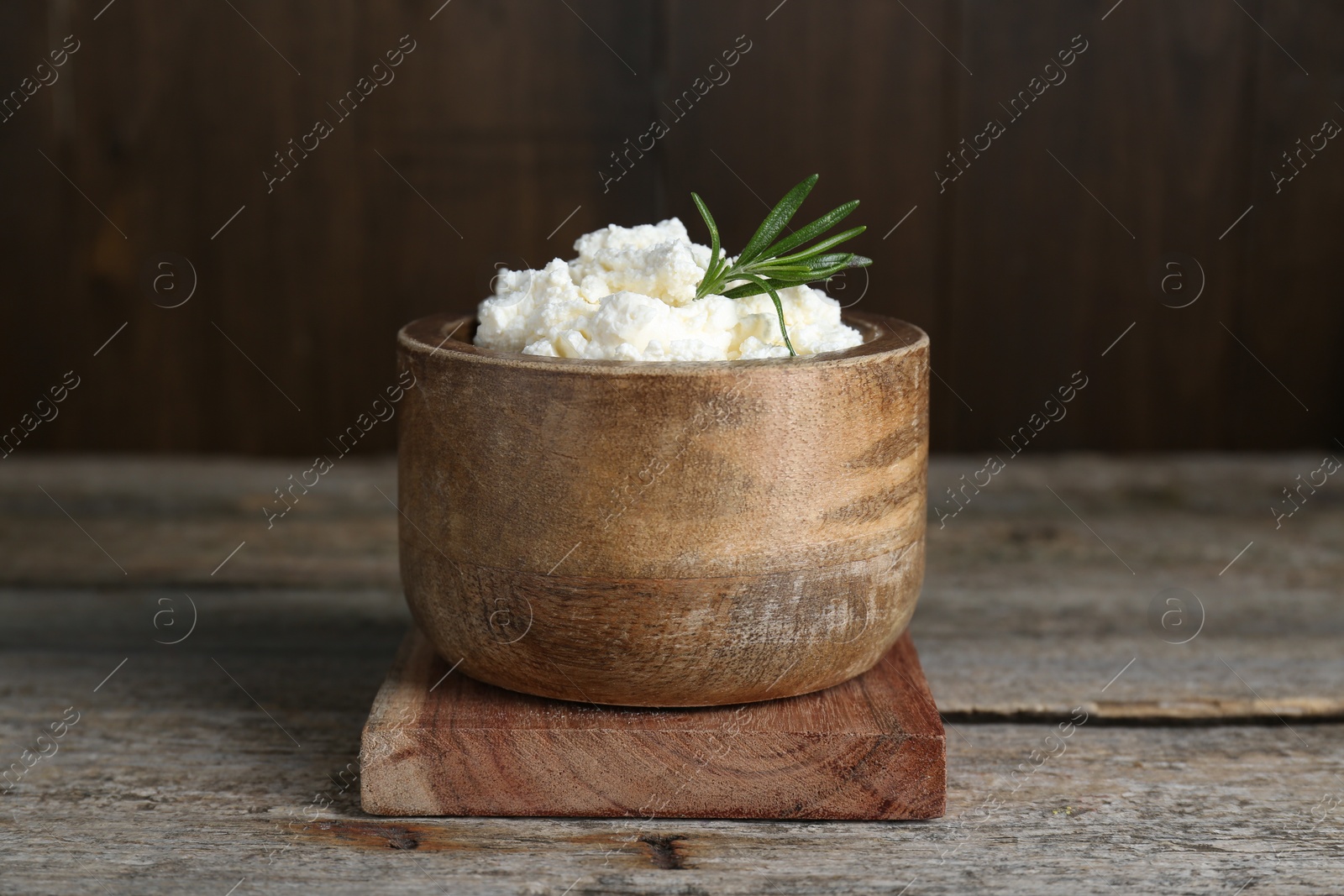 Photo of Delicious tofu cream cheese with rosemary in bowl on wooden table