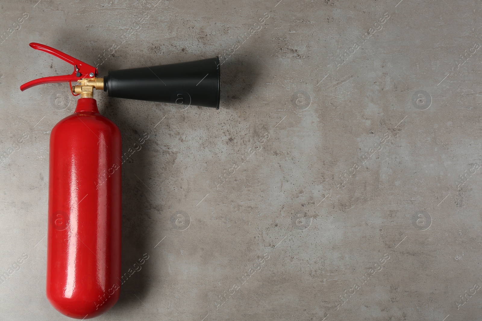 Photo of Fire extinguisher on light grey stone background, top view. Space for text