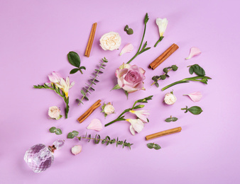 Beautiful flat lay composition with bottle of perfume, cinnamon and flowers on lilac background