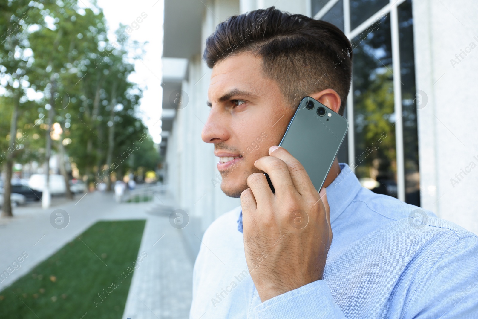 Photo of Man talking on modern mobile phone outdoors