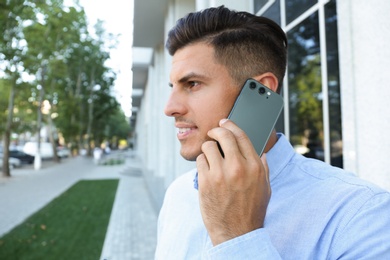 Man talking on modern mobile phone outdoors