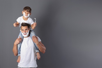 Photo of Father and son shaving on color background. Space for text