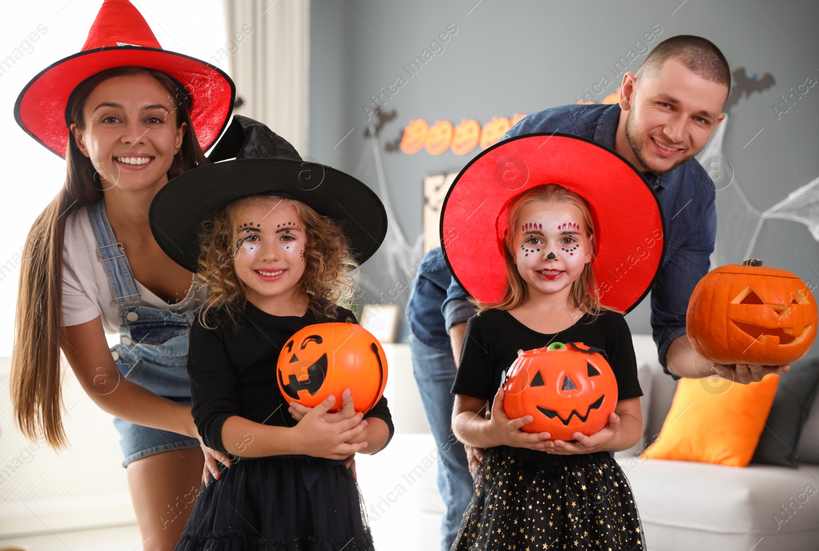 Photo of Happy family with Halloween candy buckets and pumpkin head jack lantern at home